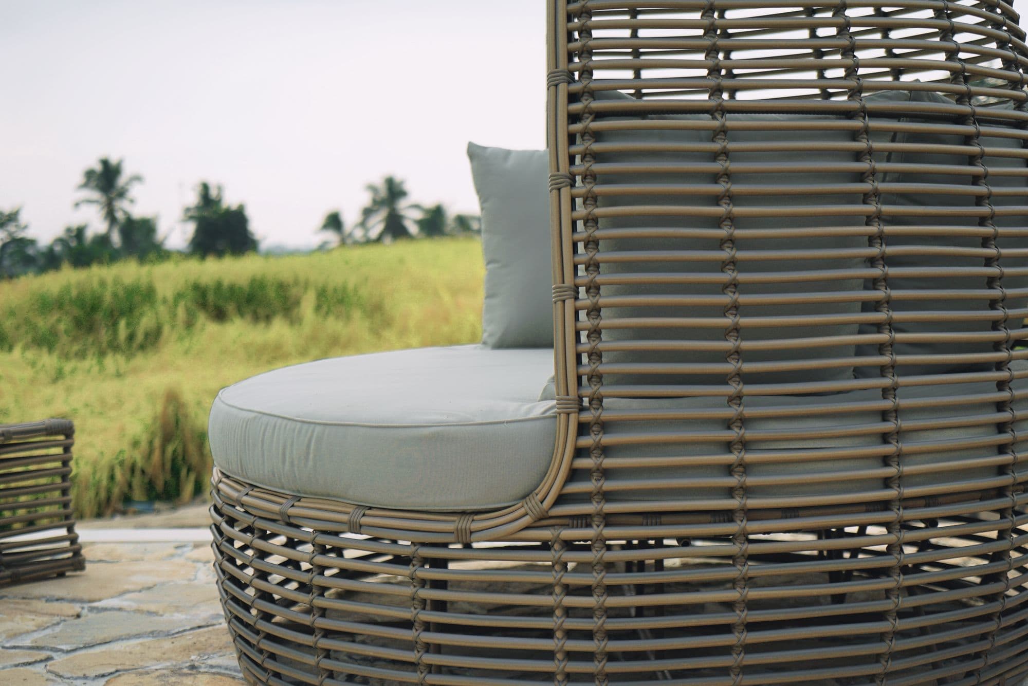 Woven lounge chair with soft cushions on the terrace